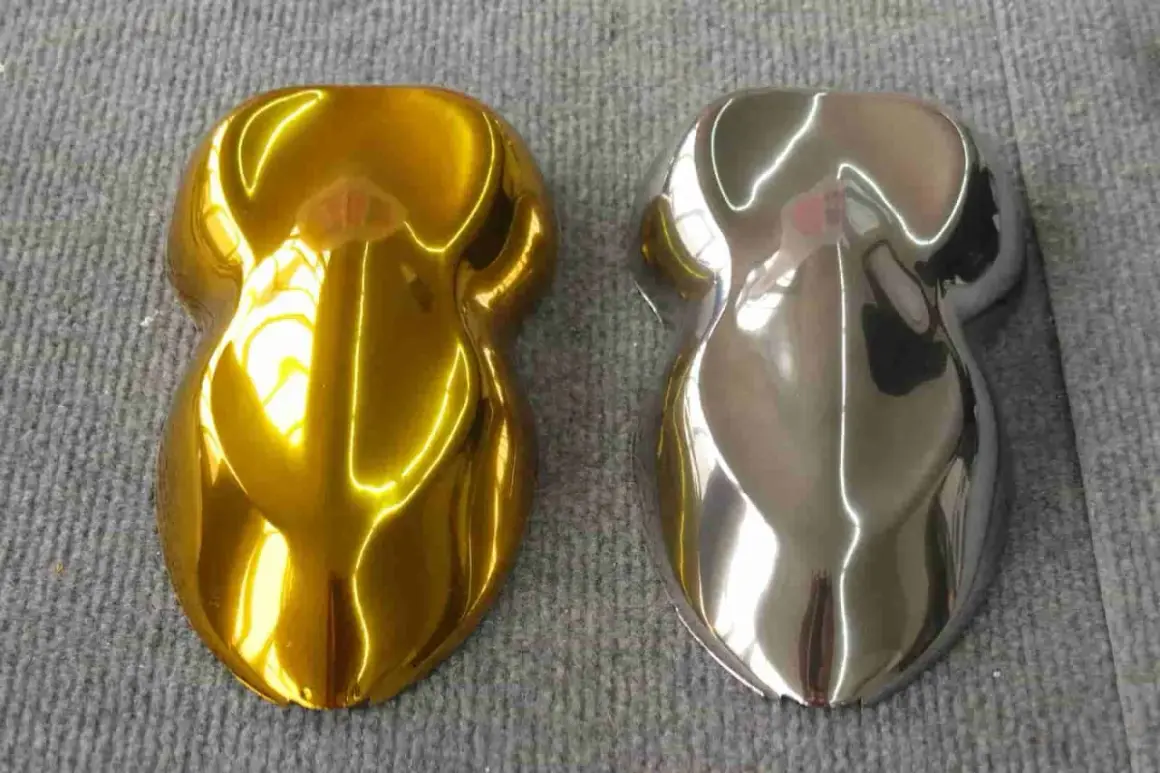 Due campioni di vernice, uno oro brillante e l'altro con un effetto cromo colore metallico, riflettono la luce su una superficie grigia.