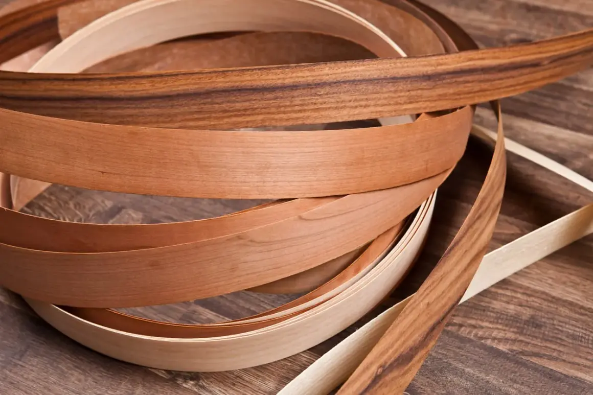 Nastri di impiallacciatura in legno di diverse tonalità, con un effetto plastica che ne esalta la texture naturale.