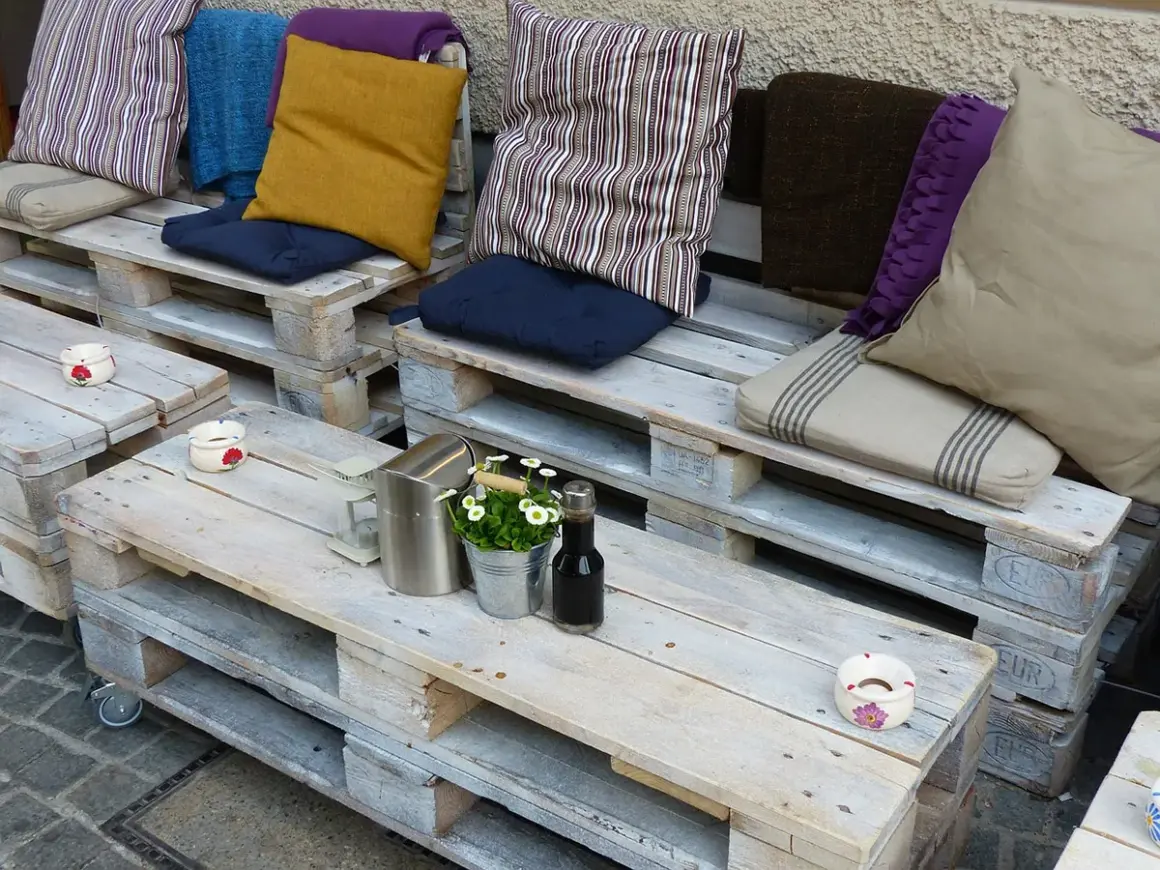 Un accogliente divano fai da te realizzato con pallet, decorato con cuscini colorati e un tavolino, perfetto per un angolo relax.