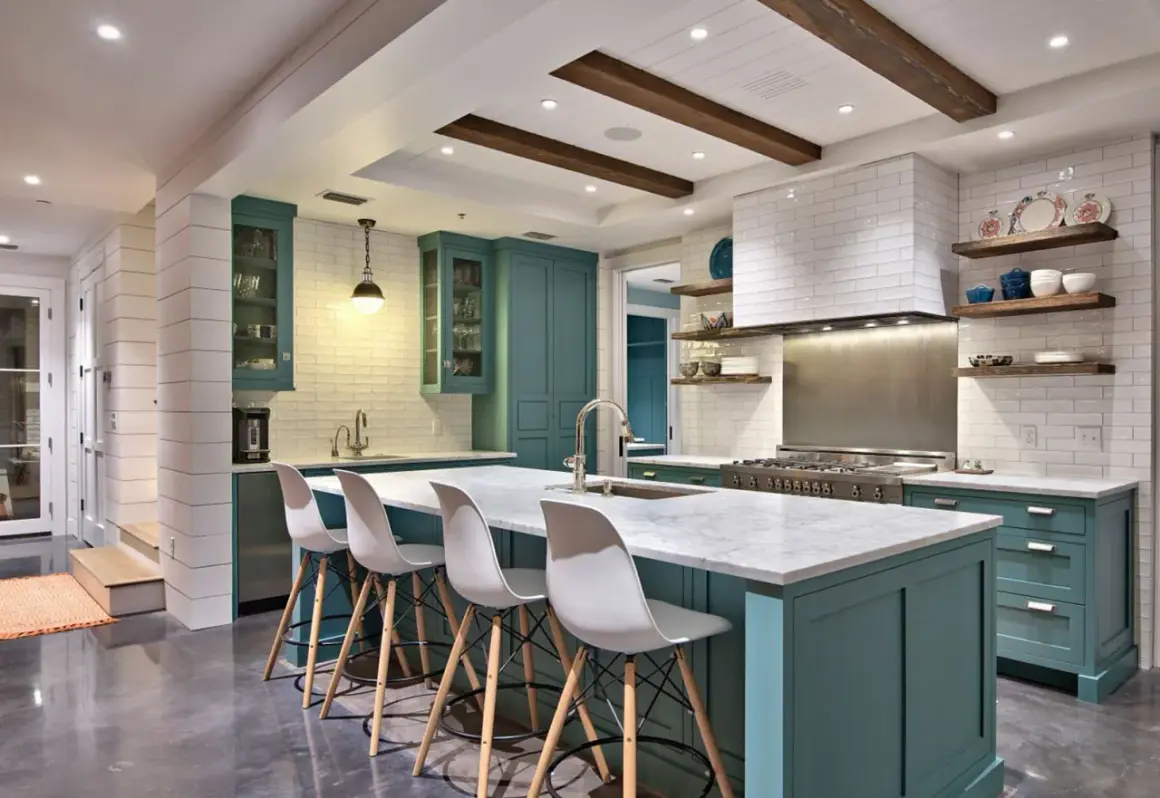 Cucina moderna con isola centrale, sgabelli bianchi e mobili color petrolio. La scelta tra meglio vernice opaca o lucida per i pensili è un dettaglio che fa la differenza.