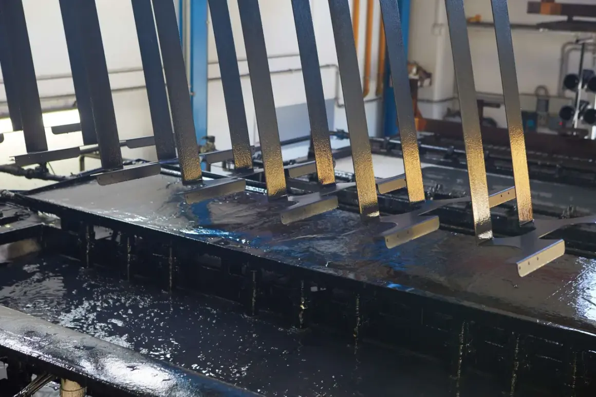 Parti metalliche immerse in un bagno per il trattamento fosfatante, pronte per la verniciatura.