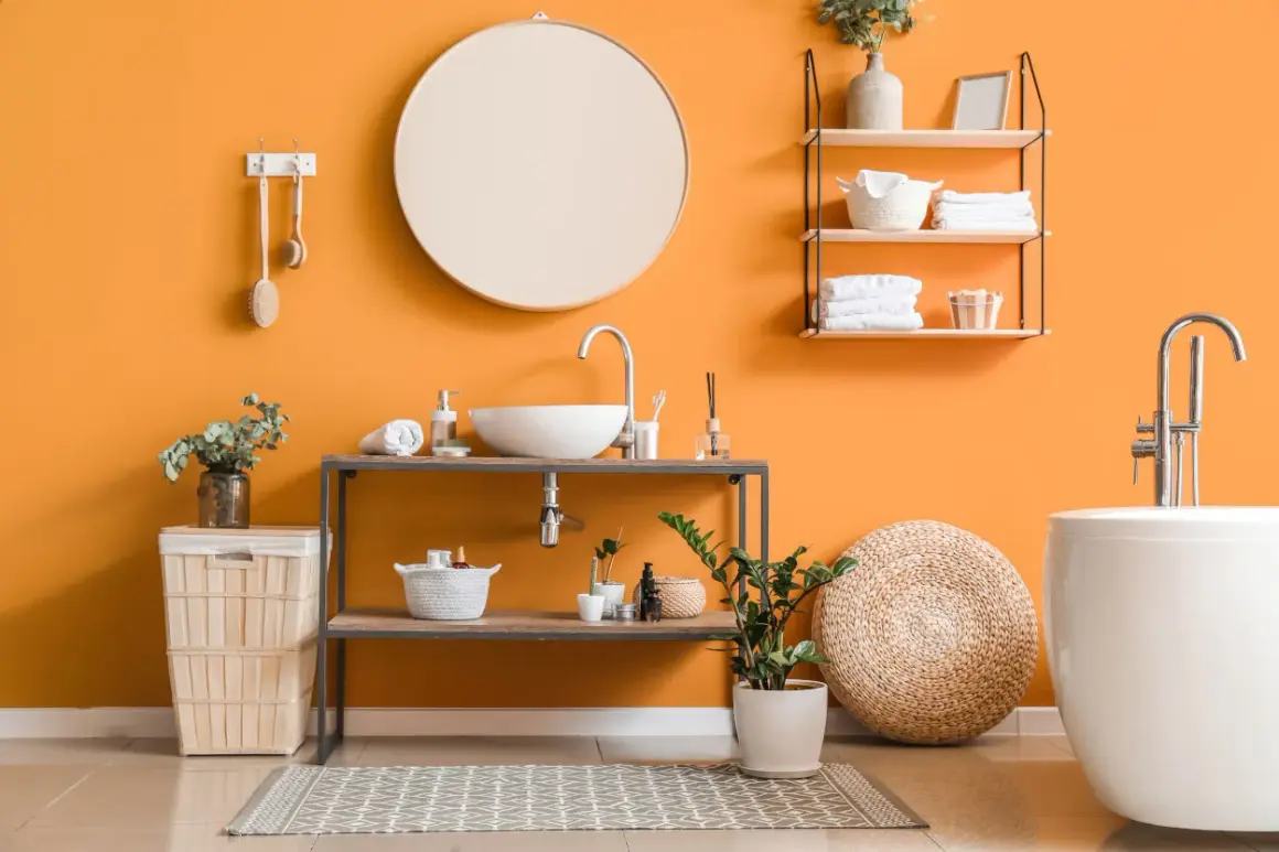 Bagno moderno con pareti arancioni vivaci, lavabo, vasca e accessori che creano un'atmosfera accogliente. I colori per bagno sono scelti con cura per un ambiente rilassante.
