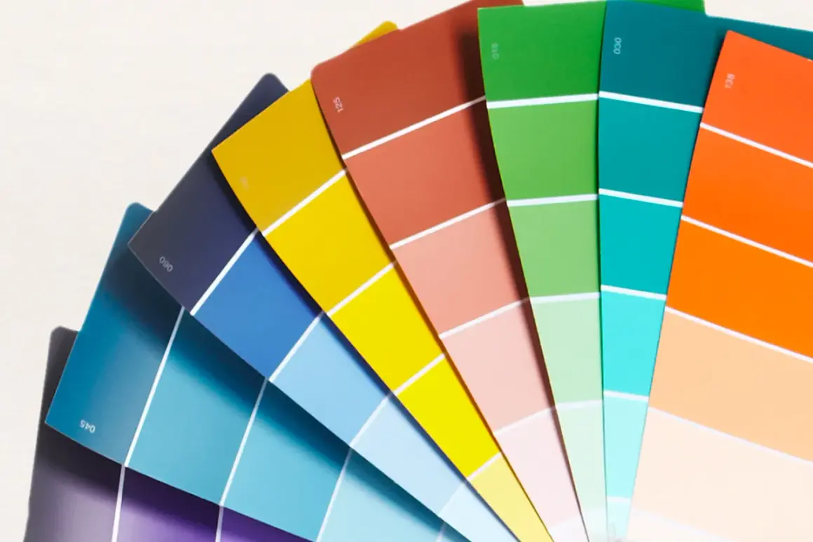 Ventaglio di campioni di colore, un tintometro manuale con sfumature vivaci dal blu al rosso, verde, arancione e giallo.