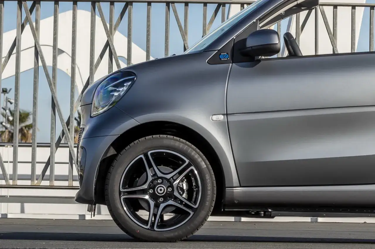 Smart EQ fortwo con vernice opaca auto grigio metallizzato, inquadrata sul lato, con cerchi in lega neri e argento.