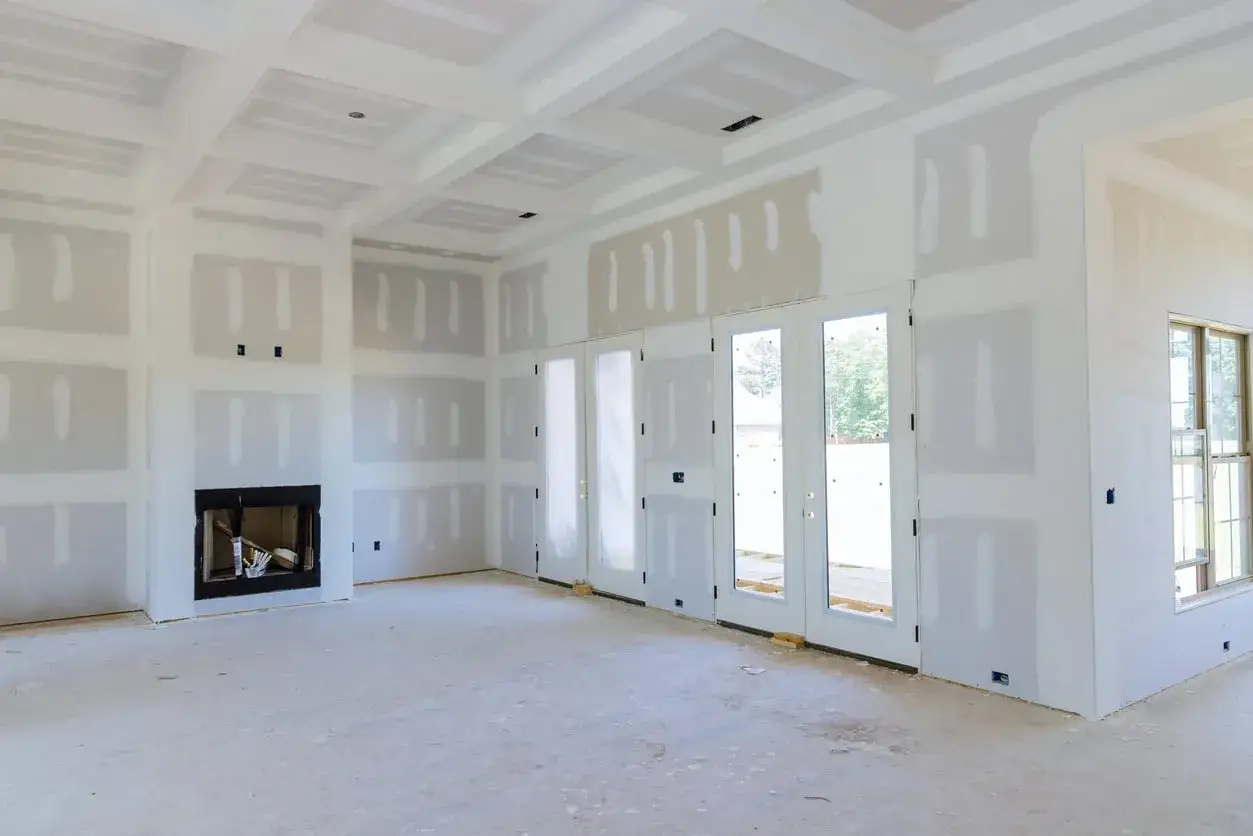 Interno di una casa in costruzione, con pareti e soffitto in cartongesso pronti per essere stuccati. Si intravede un camino.