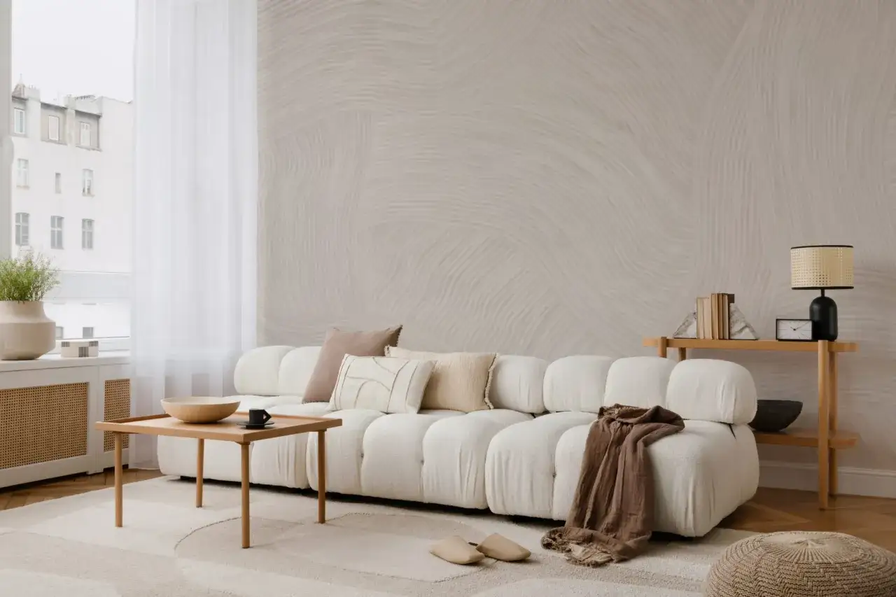 Soggiorno con divano bianco bouclé, tavolino in legno e tappeto con motivi organici. La palette japandi crea un'atmosfera serena.