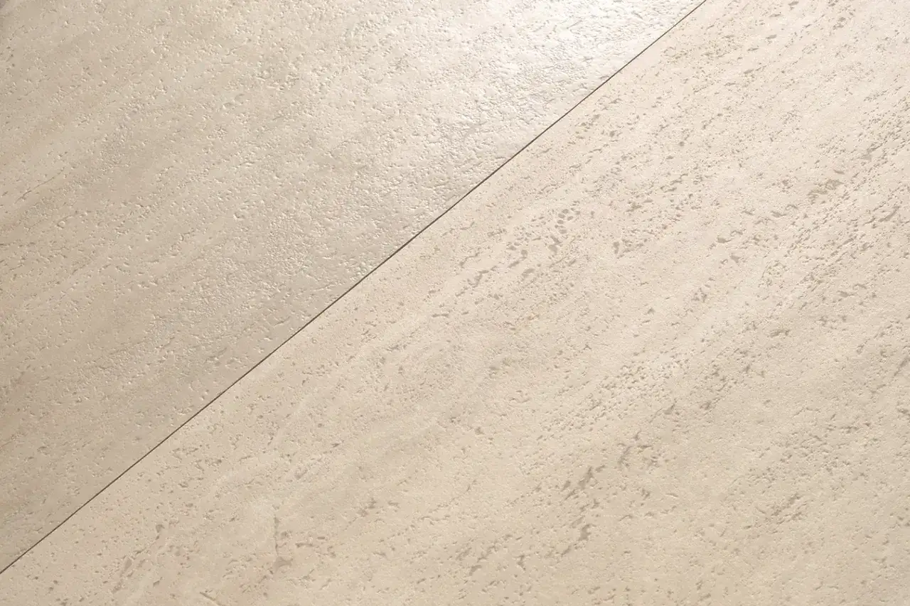 Superficie in pietra chiara, con texture irregolare, che appare sia satinato che opaco, divisa da una linea diagonale.