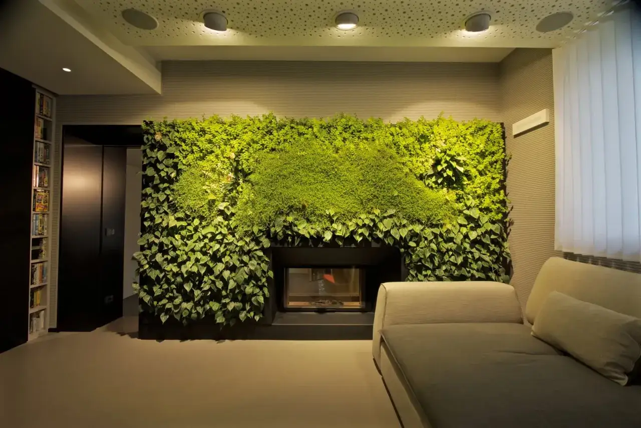 Un camino moderno incorniciato da una parete verde lussureggiante, un vero e proprio stile urban jungle che porta la natura in casa.