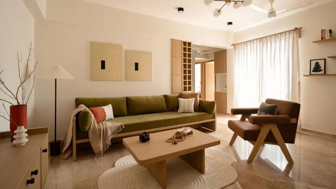 Soggiorno in stile japandi con divano verde, poltrona marrone, tavolino in legno e decorazioni minimaliste.