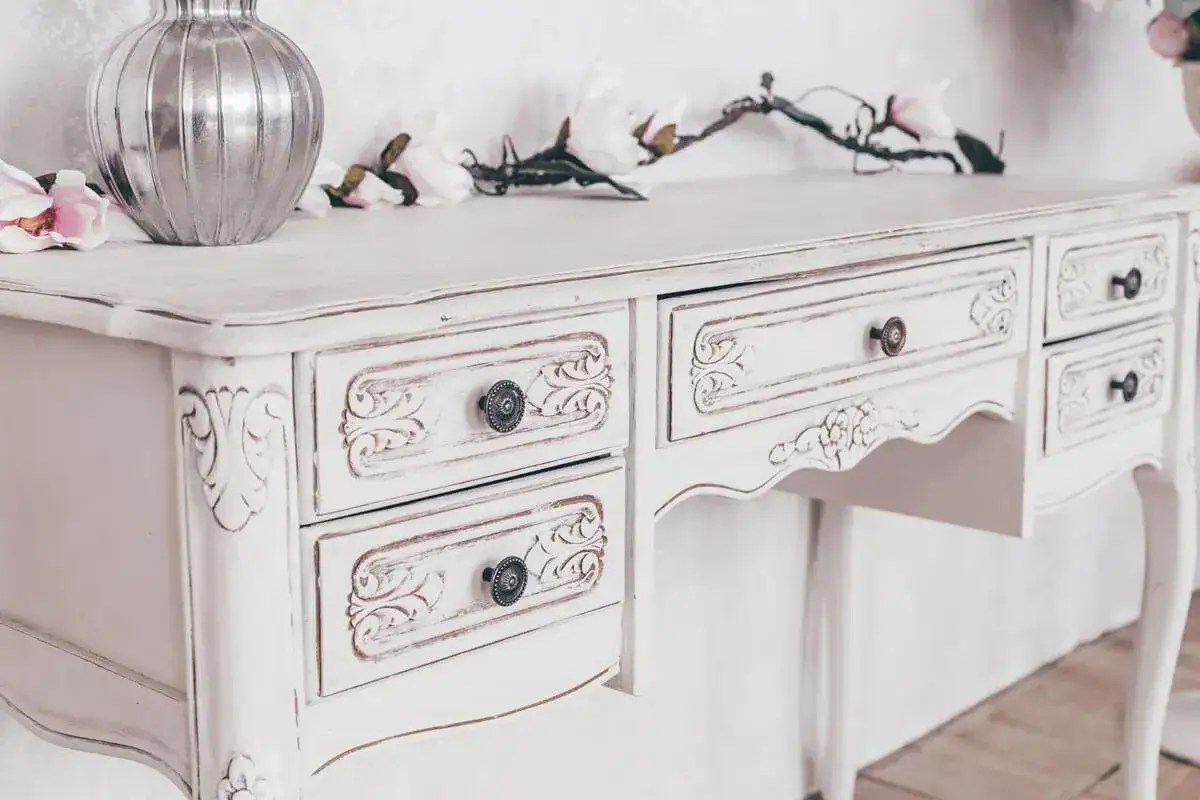 Un mobile da marrone a bianco, con dettagli intagliati e pomelli antichi. Un esempio di come verniciare un mobile per un look shabby chic.