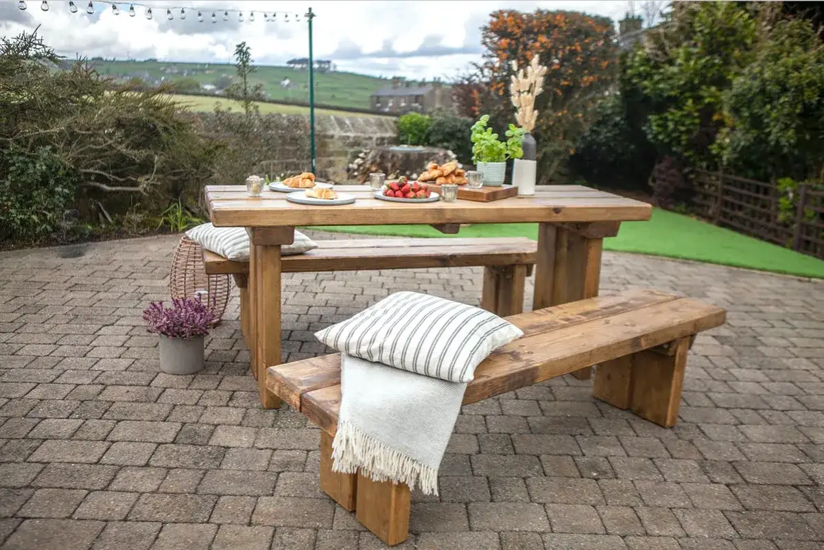 Un tavolo da giardino fai da te in legno massiccio, pronto per un picnic con croissant e fragole.