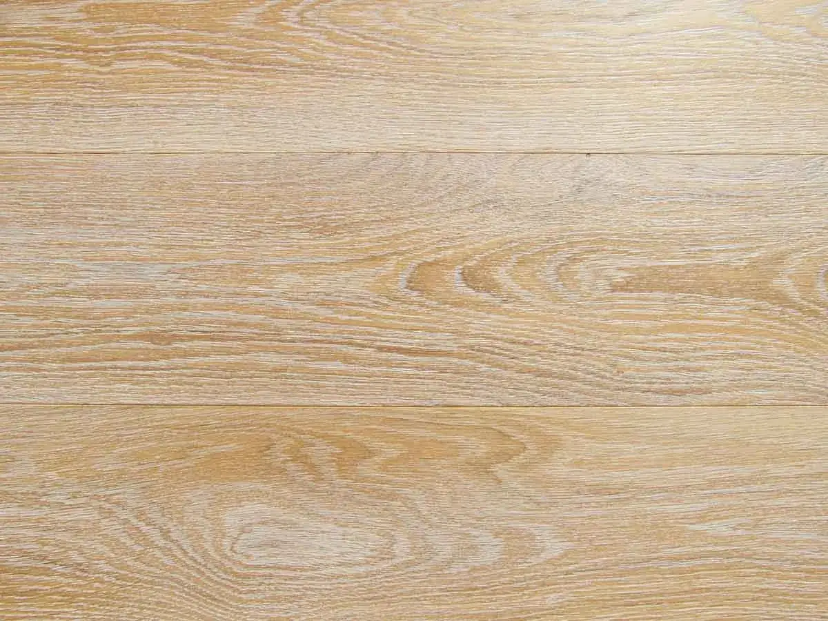 Superficie di assi in legno decapato con venature chiare e texture naturale, che evoca un'atmosfera rustica e luminosa.