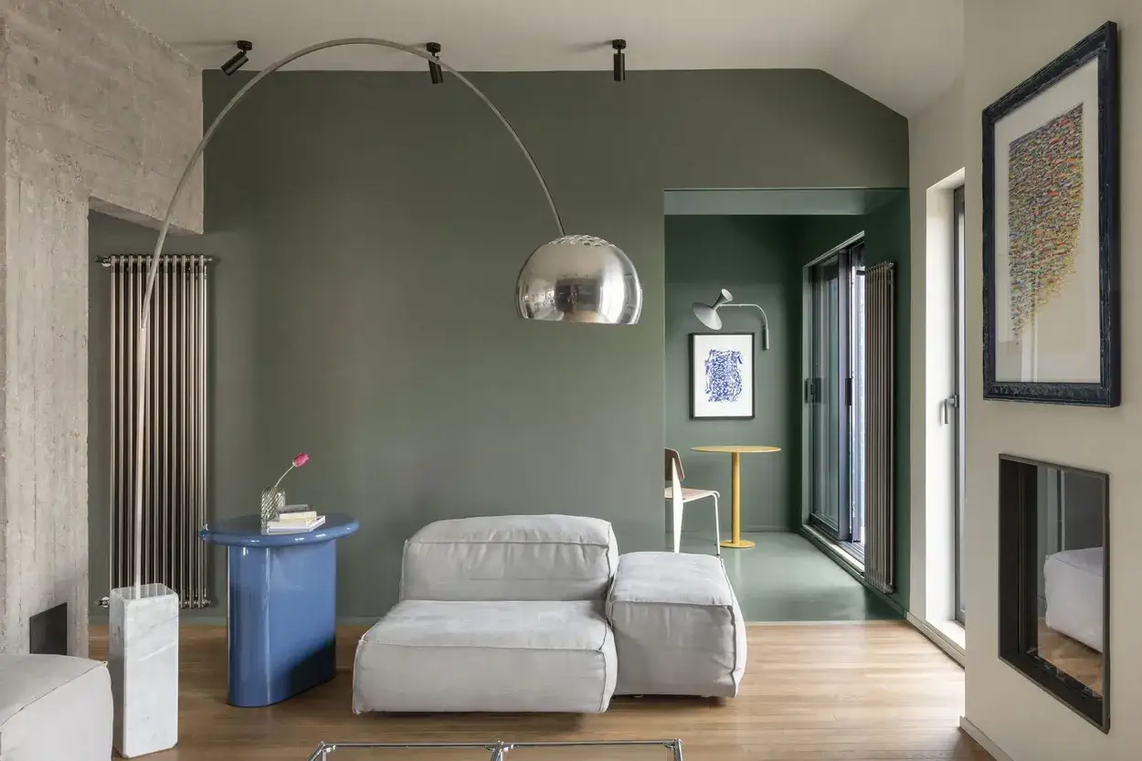 Elegante soggiorno con pareti verde salvia e un tavolino blu acceso. L'abbinamento verde salvia e blu crea un'atmosfera rilassante e sofisticata.