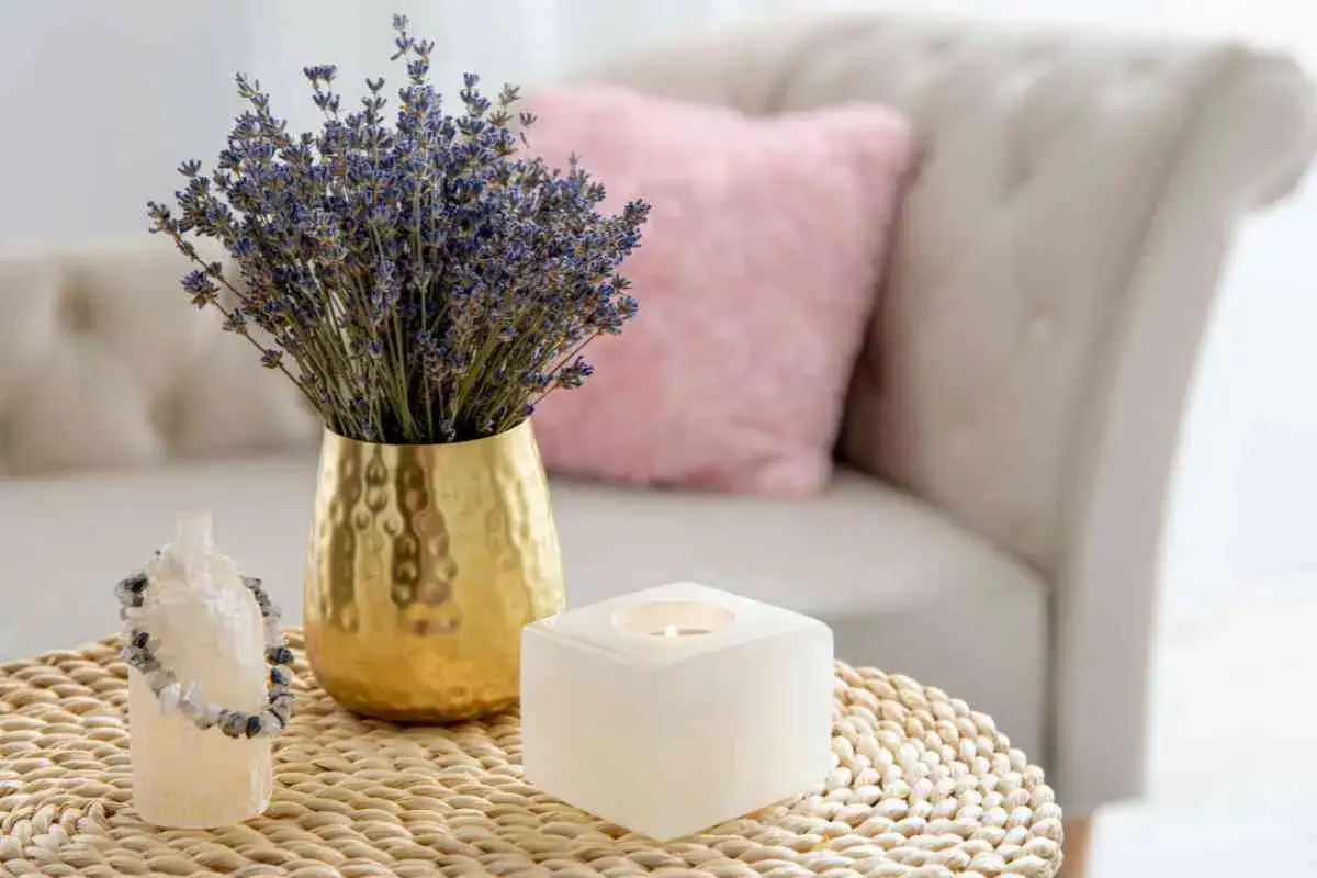 Un bouquet di lavanda in vaso dorato, una candela accesa e un bracciale su un tavolino in vimini, evocano un'atmosfera di stile provenzale francese.