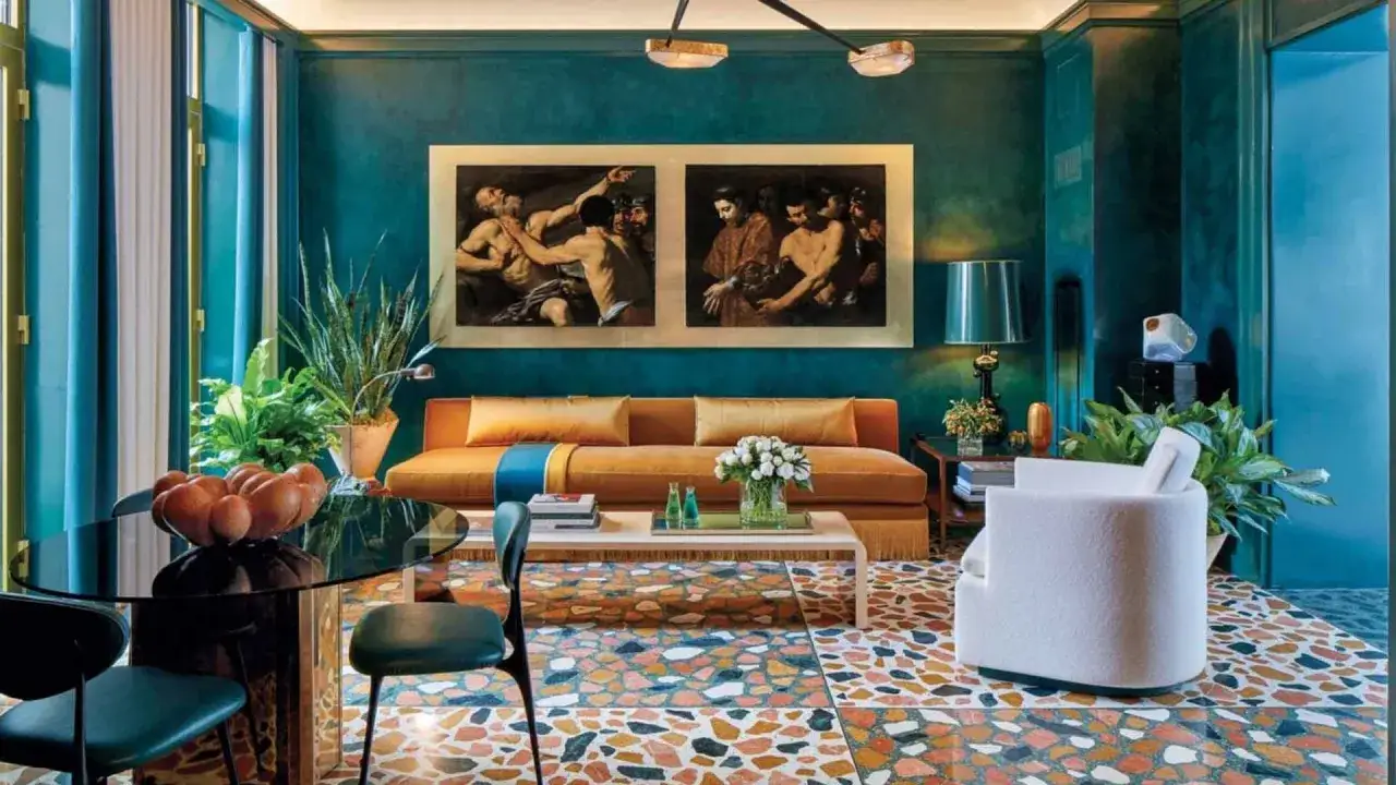 Soggiorno lussuoso con divano arancione, quadri classici e pavimento a terrazzo. La differenza tra ottanio e petrolio è come il colore di questo ambiente, ricco e profondo.