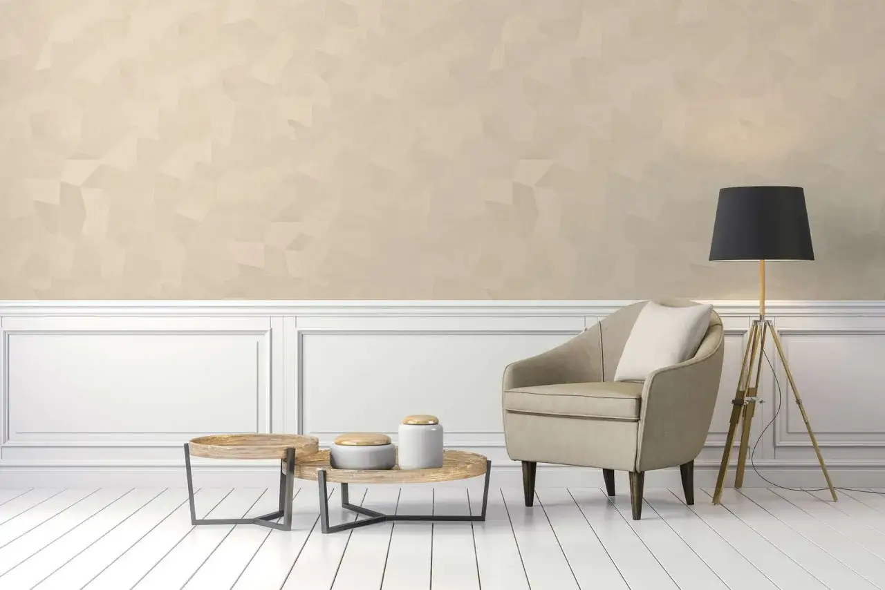 Poltrona beige sabbia color tortora chiaro ral, tavolini in legno, lampada da terra con paralume nero e parete decorata.