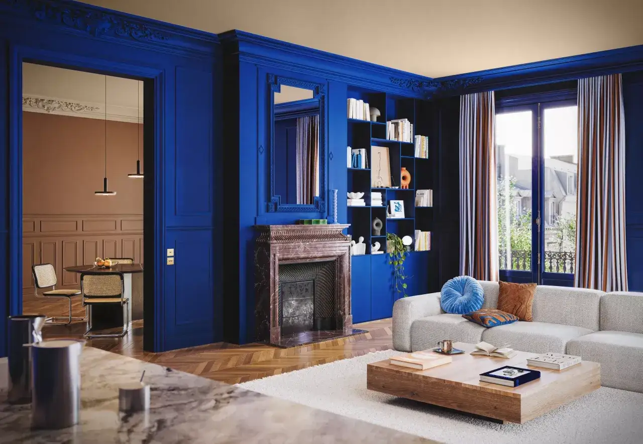 Un soggiorno elegante con pareti e libreria di un intenso colore blu. Un camino in marmo e un divano chiaro completano l'arredamento.