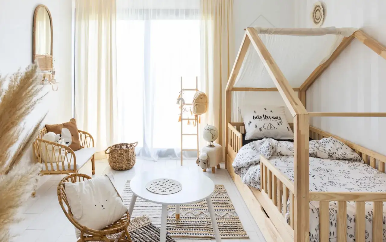 Cameretta neonato moderna con letto a casetta in legno, mobili in rattan e decorazioni naturali.