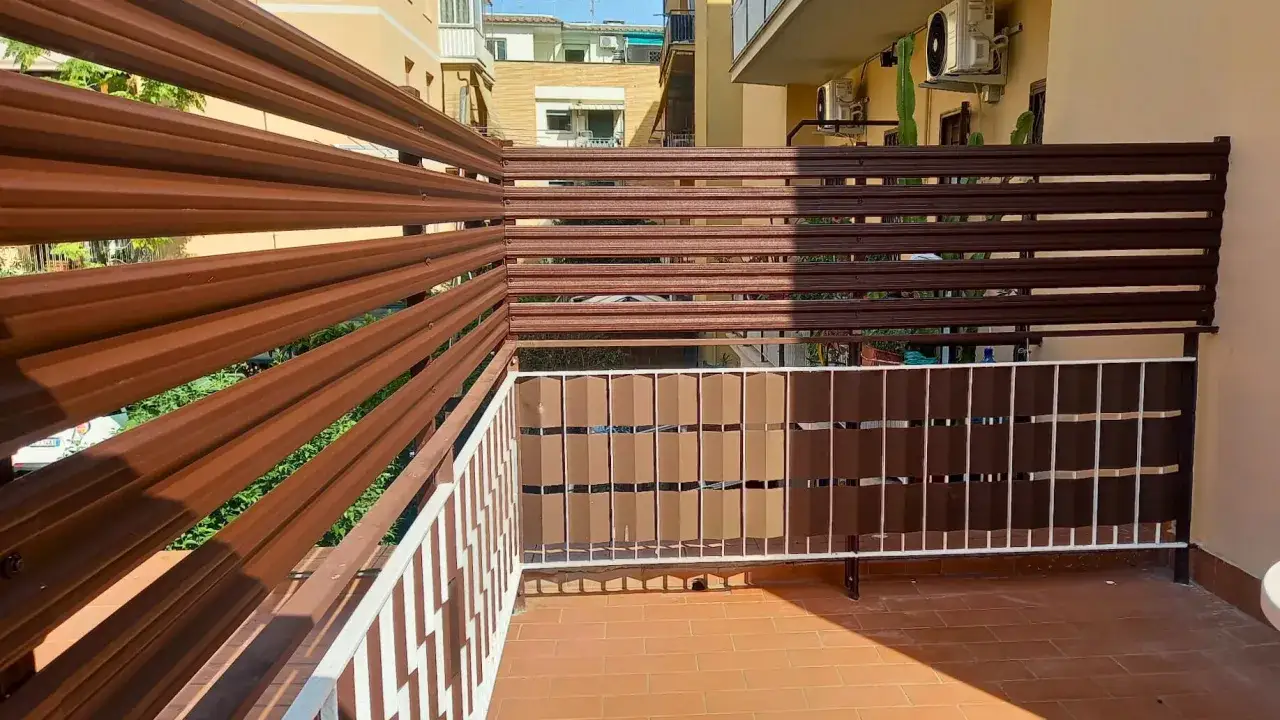 Schermo frangivista per balcone in metallo marrone, con pannelli decorativi e ringhiera bianca. Ottime idee frangivista balcone per privacy.