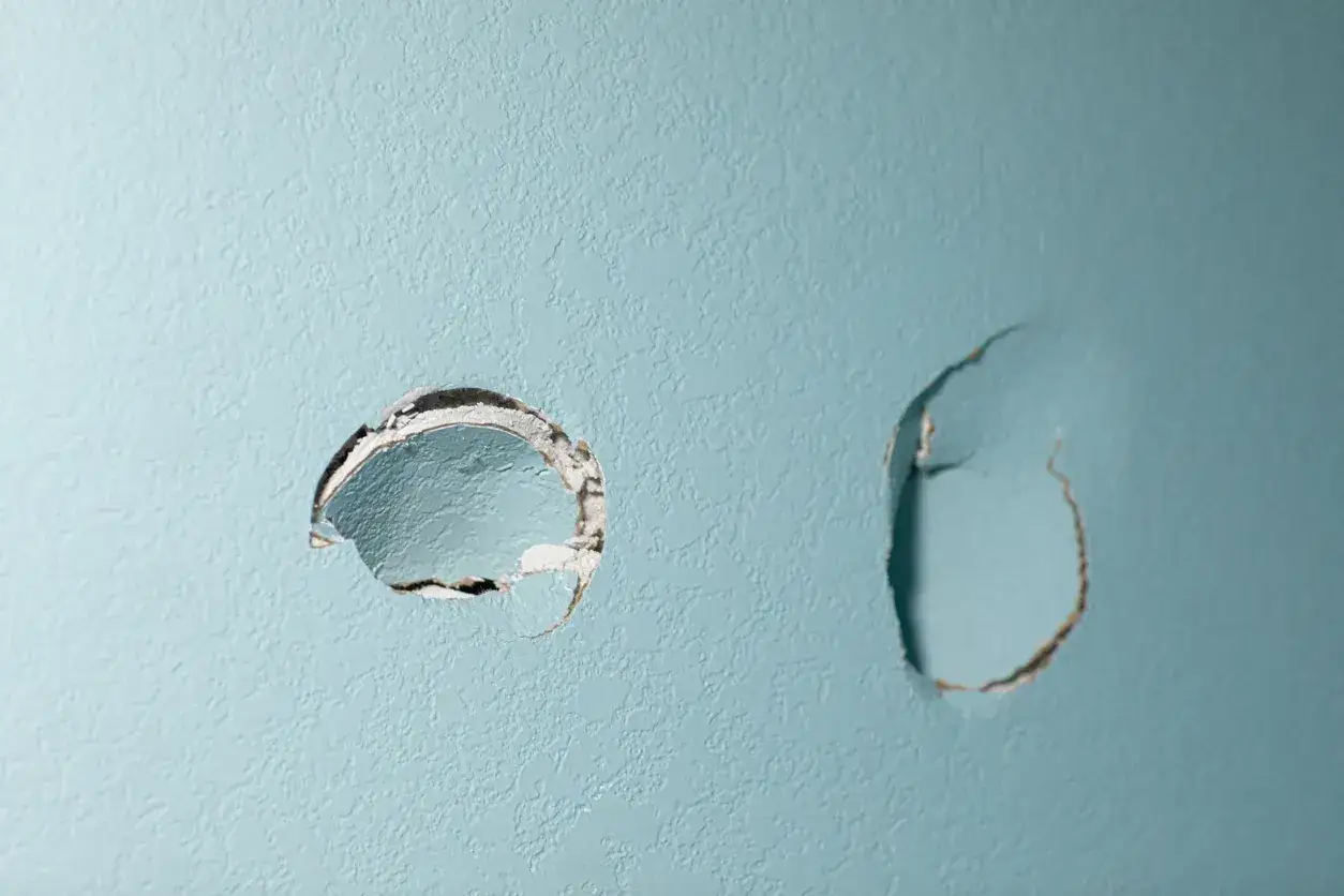 Due buchi nel muro azzurro, un problema comune per chi cerca come chiudere i buchi nel muro senza stucco.