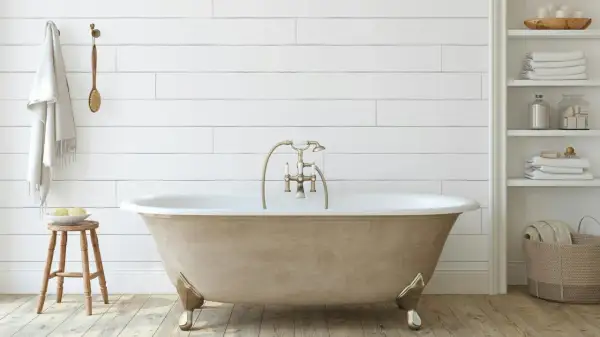 Bagno moderno con vasca da bagno color sabbia, rubinetteria dorata e asciugamani bianchi. Un progetto di verniciare vasca da bagno per un look rinnovato.