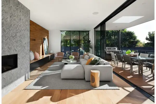 Soggiorno moderno con camino in pietra, parete in legno e diverse tipologie di legno per pavimenti e arredi.