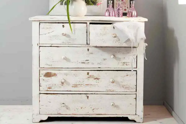 Comò in legno decapato bianco, con cassetti consumati che raccontano storie di un tempo.