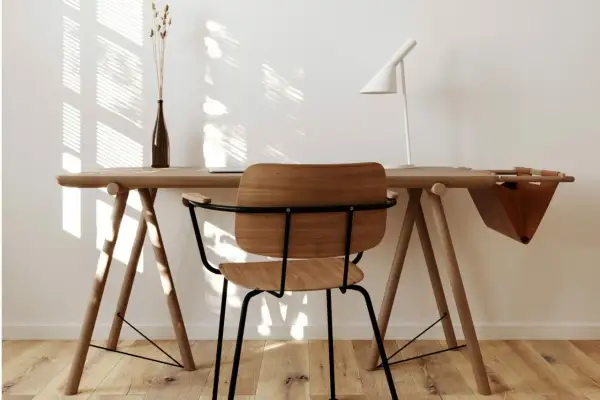 Scrivania in legno chiaro con sedia, lampada bianca e vaso. Perfetti colori da abbinare al legno chiaro per un ambiente luminoso e naturale.